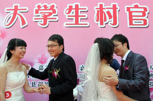 Two pairs of bridegrooms and brides exchange pledges of keepsake and embrace, during a collective wedding on the title of Love at Grassroot and Affection Devoted at Yaozhuang Village, in which 18 pairs of graduates-turned-village cadres swear in their matrimony, on the Peach Blossom Island in Yaozhuang Town, Jiashan County, east China's Zhejiang Province, March 28, 2010. (Xinhua/Hu Lingxiang)