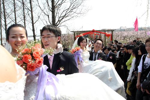 Bridegrooms carry their brides in arms to walk onto bridge of merry marriage, during a collective wedding on the title of Love at Grassroot and Affection Devoted at Yaozhuang Village, in which 18 pairs of graduates-turned-village cadres swear in their matrimony, on the Peach Blossom Island in Yaozhuang Town, Jiashan County, east China's Zhejiang Province, March 28, 2010. (Xinhua/Hu Lingxiang)