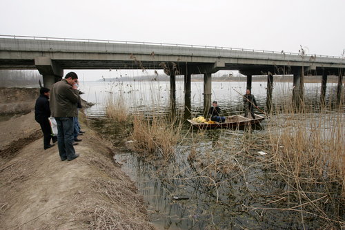 Men search for more bags of bodies under the Gunagfuhe bridge in a village in Jining county, Shandong province, on March 28. [Photo/CFP]