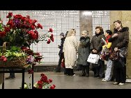 People stand in front of flowers in memory of the bomb victims at the Cultural Park subway station in Moscow, capital of Russia, March 29, 2010. [Xinhua]