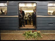 People stand in front of flowers in memory of the bomb victims at the Cultural Park subway station in Moscow, capital of Russia, March 29, 2010. [Xinhua]