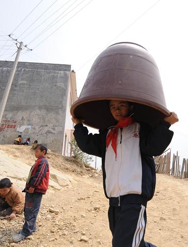 A child takes a container for holding water at Nasha Primary School in Sanbao Township of Tian&apos;e County, southwest China&apos;s Guangxi Zhuang Autonomous Region, March 29, 2010. [Xinhua]