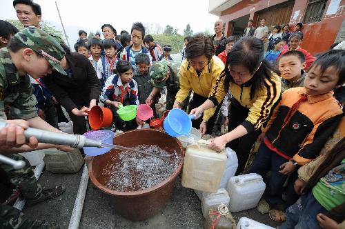 Children queue for water at Nasha Primary School in Sanbao Township of Tian'e County, southwest China's Guangxi Zhuang Autonomous Region, March 29, 2010. [Xinhua]