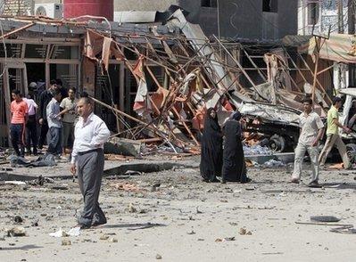 Iraqis inspect the scene of a bomb attack in central Karbala, 80 kilometers (50 miles) south of Baghdad, Iraq, Monday, March 29, 2010. A pair of car bombs went off in the holy city of Karbala.