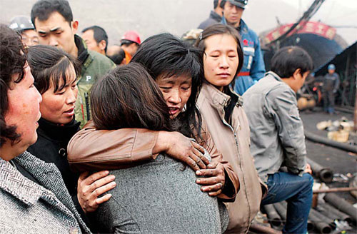 Xiao Shihong (in brown jacket) and Luo Jiangxia console each other on Tuesday as they wait outside the Wangjialing Coal Mine where both their husbands are trapped. [YANG SHIZHONG / CHINA DAILY]