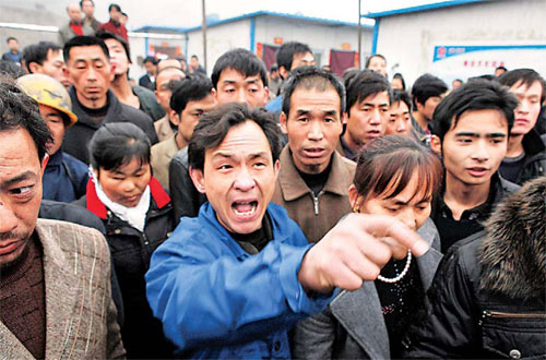 Angry relatives of miners gather outside Wangjialing Coal Mine as rescuers attempt to save victims of the disaster. [GEMUNU AMARASINGHE / ASSOCIATED PRESS]