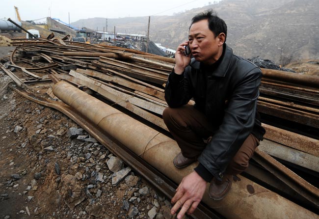 Safety supervision staffer Fu Zhaocai talks on the phone with a relative of miner trapped at the site of the flooding accident of Wangjialing Coal Mine, sitting astride Xiangning County of Linfen City and Hejin City of Yuncheng City, north China&apos;s Shanxi Province, on March 30, 2010. [Xinhua]