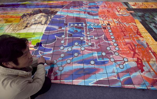 A worker checks a huge mural for the 2010 World Expo in Luoyang, central China's Henan Province, March 30, 2010. The 26-meter-long and 3.2-meter-high mural of Tang Tri-colored pottery for the Henan Pavilion in Expo Park will be packed and transported to Shanghai.