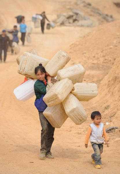 A woman carries water casks in Tian'e county of south China's Guangxi Zhuang Autonomous Region, on March 29, 2010. More than three million residents are suffering from water shortage in Guangxi which was hit by the worst drought in a century. [Xinhua]