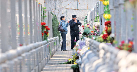 Chinese people visit the grave of a departed loved one at the Babaoshan Revolutionary Cemetery in Beijing. The cemetery is reserved for national heroes, which includes American doctor George Hatem. [Zou Hong / China Daily] 