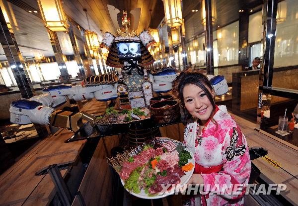 Lapassarada Thanaphant poses with a bowl of food and her robot waiter at her Hajime restaurant during its opening ceremony in Bangkok April 1, 2010. Lapassarada said she spent 30 million baht (US$927,600) on the Japanese restaurant including the purchase of four robots from Japan. [Xinhua/Reuters]