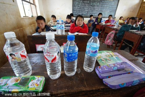 Four bottles of water are seen on the desk at a local school in Xundian autonomous county, in Southwest China's Yunnan province on March 31, 2010. The Chinese government's anti-drought efforts have eased the drinking water shortages in drought-hit areas, and the drought is not severe enough to warrant the relocation of residents. [CFP]