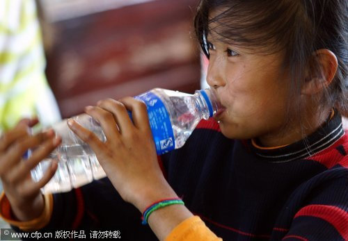 A girl drinks a bottle of water at a local school in Xundian autonomous county, in Southwest China's Yunnan province on March 31, 2010. [CFP]