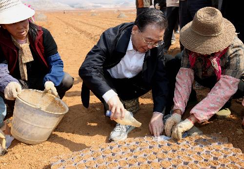Chinese Premier Wen Jiabao (C) adds soil to the plastic bags to rear corn seedlings in the field in Luliang County, southwest China&apos;s Yunnan Province, March 20, 2010. During a three-day inspection trip in the drought-plagued Yunnan Province ending on Sunday, Premier Wen visited Qujing City, one of the regions that suffered the most from the severe drought ravaging since last October, to comfort the affected locals and direct relief work. [Xinhua]