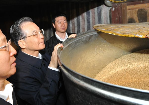 Chinese Premier Wen Jiabao examines the surplus grain at villager Yang Wenming's house at Nalai Village of Anlong County in the Qianxinan Buyei and Miao Autonomous Prefecture, southwest China's Guizhou Province, April 4, 2010.[Xinhua]
