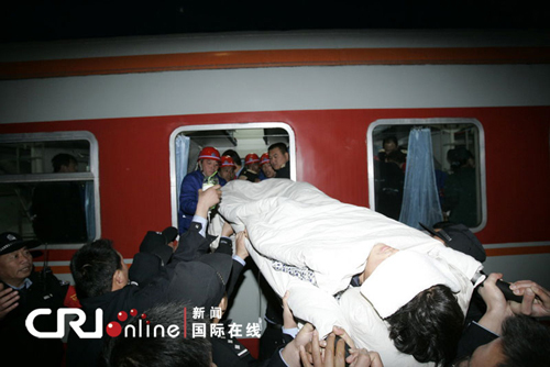 A rescued miner in relatively serious condition is carried on a stretcher into a train at the railway station in Hejin City, north China's Shanxi Province, April 6, 2010. Sixty of the 115 workers who were pulled out alive after being trapped for over a week in the flooded Wangjialing Coal Mine were transferred to key hospitals in the provincial capital Taiyuan Tuesday to receive better treatment. [CRI photo]