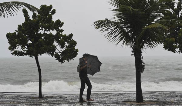 A tourist holds an umbrella as he walks along windy Ipanema beach in Rio de Janeiro. At least 95 people died, 106 were injured and 1,410 were left homeless in a storm that devastated Brazil&apos;s southeastern state of Rio de Janeiro since Monday evening, authorities said Tuesday.[Xinhua]