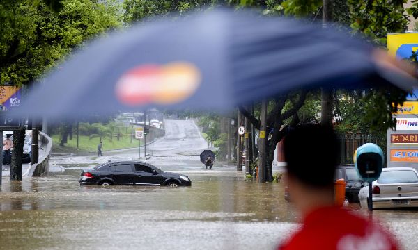 A man walks through a flooded street near Rodrigo de Freitas lake in Rio de Janeiro April 7, 2010.[Xinhua]