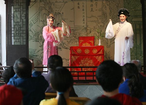  A pair of performers entertain the excursionists with episodes of traditional Kunqu Opera, inside the Liuyuan Garden of Suzhou, east China's Jiangsu Province, April 5, 2010. The renowned Suzhou Garden put on series of tourist programme typical of local Wu Culture to lure tourists from both home and overseas during the vacationing of Qingming Festival. [Xinhua]