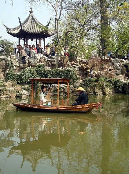 A performer sitting inside an archaic style boat entertains the excursionists with Suzhou Pingtan, a typical folklore art form of ballad-singing and story-telling, inside the Liuyuan Garden of Suzhou, east China's Jiangsu Province, April 5, 2010. The renowned Suzhou Garden put on series of tourist programme typical of local Wu Culture to lure tourists from both home and overseas during the vacationing of Qingming Festival. [Xinhua/Wang Jiankang]