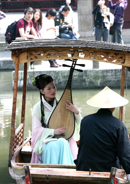 A female performer sitting inside an archaic style boat entertains the excursionists with Suzhou Pingtan, a typical folklore art form of ballad-singing and story-telling, inside the Liuyuan Garden of Suzhou, east China's Jiangsu Province, April 5, 2010. The renowned Suzhou Garden put on series of tourist programme typical of local Wu Culture to lure tourists from both home and overseas during the vacationing of Qingming Festival. [Xinhua]