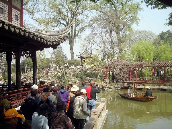 Visitors swarm on the bank to enjoy a performer sitting inside an archaic style boat performing Suzhou Pingtan, a typical folklore art form of ballad-singing and story-telling, inside the Liuyuan Garden of Suzhou, east China's Jiangsu Province, April 5, 2010. The renowned Suzhou Garden put on series of tourist programme typical of local Wu Culture to lure tourists from both home and overseas during the vacationing of Qingming Festival. [Xinhua/Wang Jiankang] 