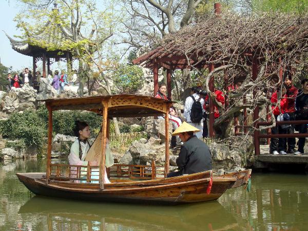 A performer sitting inside an archaic style boat entertains the excursionists with Suzhou Pingtan, a typical folklore art form of ballad-singing and story-telling, inside the Liuyuan Garden of Suzhou, east China's Jiangsu Province, April 5, 2010. The renowned Suzhou Garden put on series of tourist programme typical of local Wu Culture to lure tourists from both home and overseas during the vacationing of Qingming Festival. [Xinhua/Wang Jiankang] 