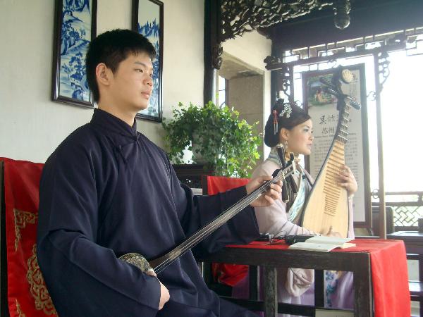 A pair of performers sitting inside an archaic style pavilion entertain the excursionists with Suzhou Pingtan, a typical folklore art form of ballad-singing and story-telling, inside the Liuyuan Garden of Suzhou, east China's Jiangsu Province, April 5, 2010. The renowned Suzhou Garden put on series of tourist programme typical of local Wu Culture to lure tourists from both home and overseas during the vacationing of Qingming Festival. [Xinhua/Wang Jiankang]