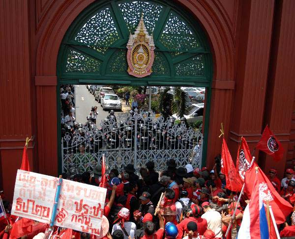Thailand's red-shirted protesters confront with policemen and soldiers at the gate of the Parliament House compound in Bangkok, capital of Thailand, April 7, 2010. Hundreds of anti-government protesters besieged the Parliament House for hours Wednesday and stormed into the compound before they withdrew and dispersed upon their leader's request. 