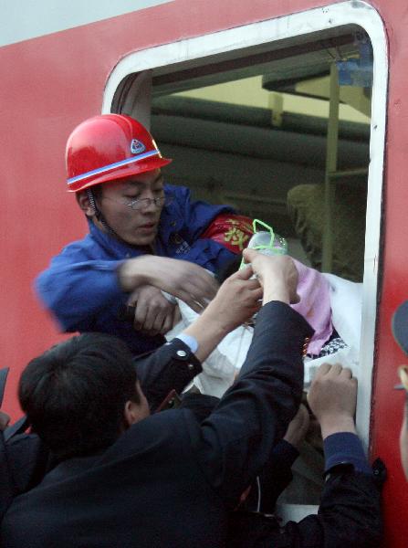 A rescued miner in relatively serious condition is carried on a stretcher into a train at the railway station in Hejin City, north China's Shanxi Province, April 6, 2010. Sixty of the 115 workers who were pulled out alive after being trapped for over a week in the flooded Wangjialing Coal Mine were transferred to key hospitals in the provincial capital Taiyuan Tuesday to receive better treatment. [Xinhua]