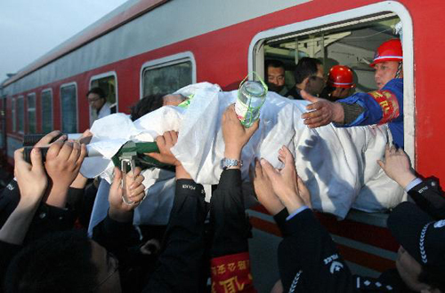 A rescued miner in relatively serious condition is carried on a stretcher into a train at the railway station in Hejin City, north China's Shanxi Province, April 6, 2010. Sixty of the 115 workers who were pulled out alive after being trapped for over a week in the flooded Wangjialing Coal Mine were transferred to key hospitals in the provincial capital Taiyuan Tuesday to receive better treatment. [Xinhua]