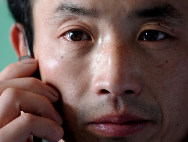 Guo Haijun, a miner who survived the Wangjialing coal mine accident, talks to his family on the phone at the Hejin Municipal People's Hospital in north China's Shanxi Province, on April 8, 2010. 