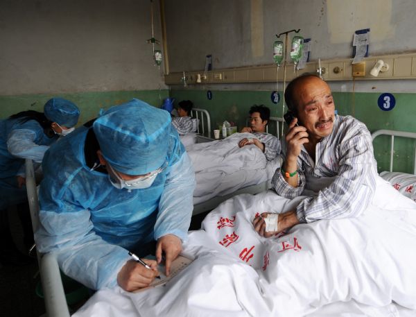 Dong Youhong, a miner who survived the Wangjialing coal mine accident, talks to his son on the phone at the Hejin Municipal People's Hospital in north China's Shanxi Province, on April 8, 2010.