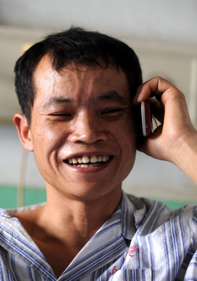 Peng Guangzhong, a miner who survived the Wangjialing coal mine accident, talks to his wife on the phone at the Hejin Municipal People's Hospital in north China's Shanxi Province, on April 8, 2010.