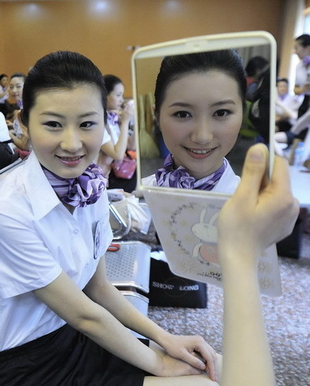 A competitor looks at herself in a mirror before going onstage during the Air Hostess Contest TV show in Wuhan, capital of Central China&apos;s Hubei province on April 7, 2010.[Photo/Xinhua]