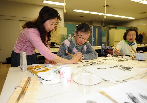 Zhang Xiaowen (L), a teacher of traditional Chinese paintings, teaches Japanese students at Confucius Institute in Kogakuyin University, Tokyo, Japan, April 8, 2010. 