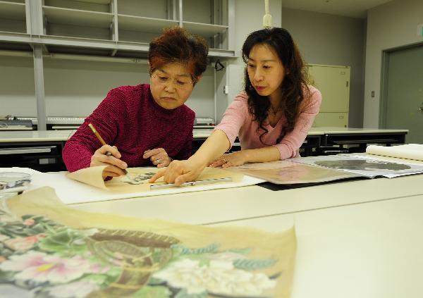 Zhang Xiaowen (R), a teacher of traditional Chinese paintings, teaches Japanese students at Confucius Institute in Kogakuyin University, Tokyo, Japan, April 8, 2010. 