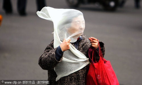 An old woman wraps a veil around her head to protect herself against hard winds in Changchun, capital of Jilin province, April 8, 2010. [CFP]