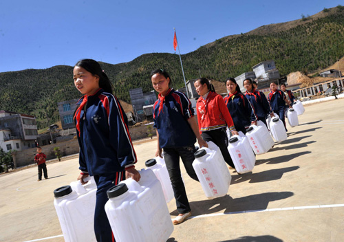 Students take big plastic bottles to get water dispatched by the local government at a school in South China&apos;s Guangxi Zhuang autonomous region on April 8, 2010. [Xinhua] 