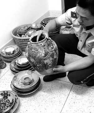 A police officer displays the pottery and porcelain artifacts salvaged from the sunken ancient merchant ship Nan'ao No 1 on June 8, 2007. [Xinhua]