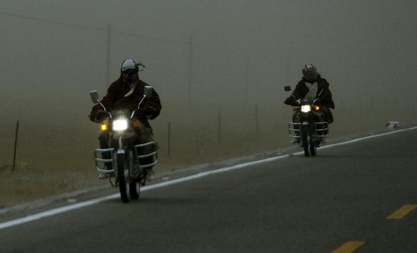 People ride motorcycles in the sandstorm beside Qinghai Lake in northwest China's Qinghai Province, April 9, 2010. A sandstorm hit Qinghai on Friday. [Hou Deqiang/Xinhua]