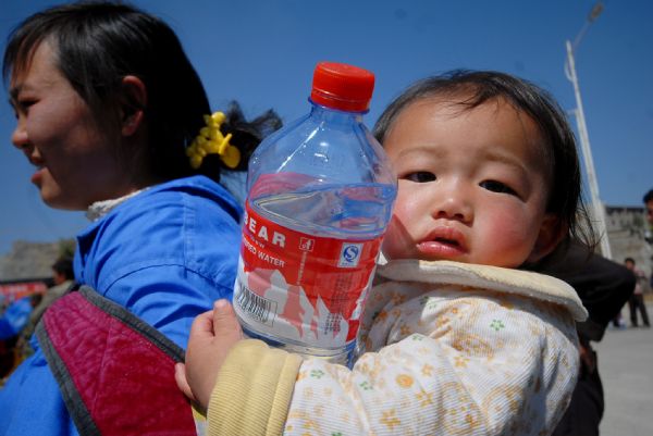 Photo taken on April. 8, 2010 shows a girl on the back of her mother holding a big bottle of drinking water they received from the relief point in Puan county, southwest China's Guizhou province. More and more relief donations , mainly drinking water, come from every corner of the whole country to the drought-ravaged region.