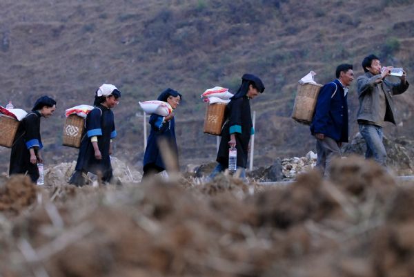 Photo taken on April. 8, 2010 shows local people carrying rice and drinking water home they received from the relief point in Puan county, southwest China's Guizhou province. More and more relief donations , mainly drinking water, come from every corner of the whole country to the drought-ravaged region.