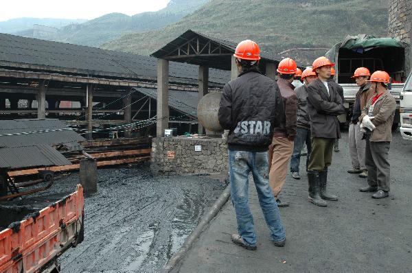 Workers stand outside the workshop where a manganese mine dreg overflow accident happened in Fengyun Manganese Co., Ltd. in Huayuan County in central China's Hunan Province, April 11, 2010. One worker was killed and five are still missing after more than 400 cubic meters of manganese mine dregs overflowed from a mine dregs retaining pond at the company Saturday. The landslide happened when 35 workers were working to close down the pond. 29 were evacuated and 6 were buried.