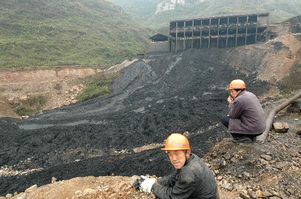 Workers squat beside a manganese mine dregs retaining pond in Fengyun Manganese Co., Ltd. in Huayuan County in central China's Hunan Province, April 11, 2010. One worker was killed and five are still missing after more than 400 cubic meters of manganese mine dregs overflowed from a mine dregs retaining pond at the company Saturday. The landslide happened when 35 workers were working to close down the pond. 29 were evacuated and 6 were buried.