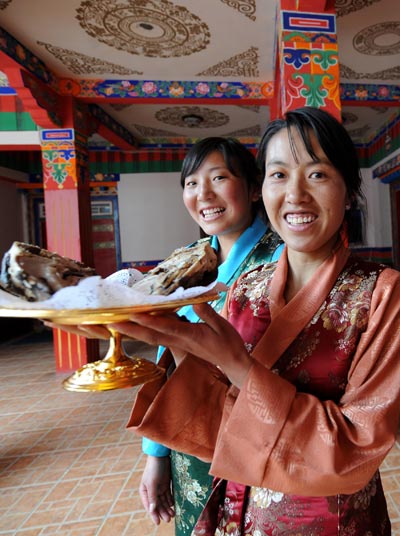 Tibetan waitresses show a Tibetan dish named Lucky Goat Head inside a Tibetan restaurant in Lhasa, capital of southwest China's Tibet Autonomous Region, April 8, 2010. Tibet is ready to meet its tourism boom. It is expected that as many as 6 million tourists will come to visit Tibet this year. [Xinhua/Chogo]
