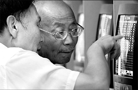 Investors check share prices at a securities trading firm in Shanghai. [China Daily]