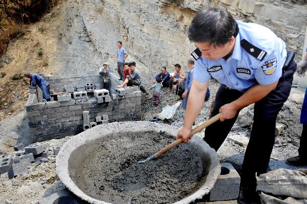 A local policeman help villagers build water tank at Jiaolong Village in Wangmo County, southwest China&apos;s Guizhou Province, April 10, 2010. As severe drought has ravaged China&apos;s southwest region since last October, leading to serious drinking water shortage of local human beings and livestocks, the local police managed to build kilometres long water pipe to help solve the problem.[Xinhua]