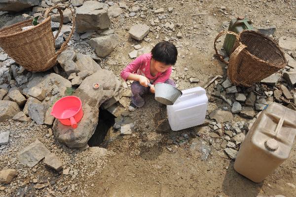 Photo taken on April 10, 2010 shows a little girl collecting water from a pit at Jiaolong Village in Wangmo County, southwest China&apos;s Guizhou Province, April 10, 2010. As severe drought has ravaged China&apos;s southwest region since last October, leading to serious drinking water shortage of local human beings and livestocks, the local police managed to build kilometres long water pipe to help solve the problem.[Xinhua]