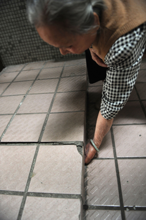 A resident inspects a crack in the fl oor of her Yuanlin residential community apartment in the Jinshazhou area of Guangzhou, capital of Guangdong province. 